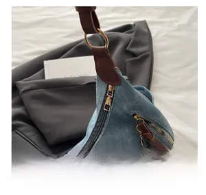 Detalle de cremallera metálica y flecos de cuero en bolso vaquero azul claro