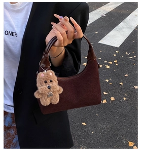 Détail du sac hobo en daim marron foncé avec poignée polie et breloque chien en peluche
