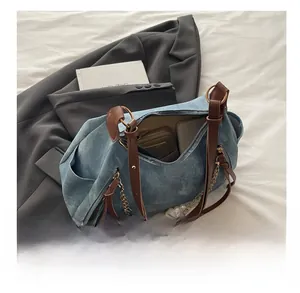 Detalle del interior espacioso del bolso denim azul con correa de cuero y perlas