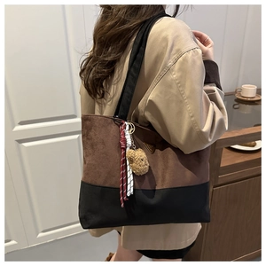 Detalle del bolso tote bicolor con logo metálico y llavero decorativo de un oso