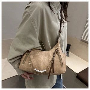 Detalle del bolso de hombro en ante caqui con perlas blancas y cadena de metal