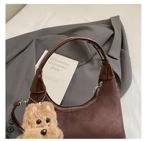 Détail du sac lune en daim marron vintage avec garniture en cuir et breloque ours