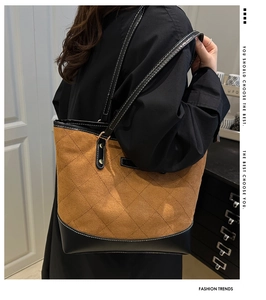 Detail of color-block tote bag featuring brown suede and black leather stitching