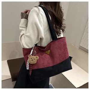 Detalle del bolso tote de pana en contraste con colgante de osito de peluche suave