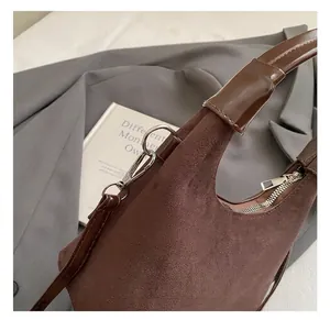 Détails du crochet métallique argenté et texture suédée sur un sac hobo marron
