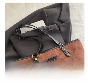 Detail of brown quilted tote bag with black leather straps and stitched logo on blazer