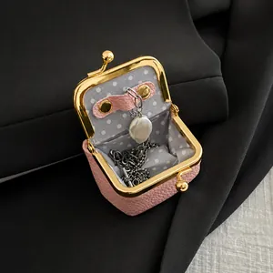 Pink pebbled leather jewelry pouch with gold clasp showing internal storage for necklace