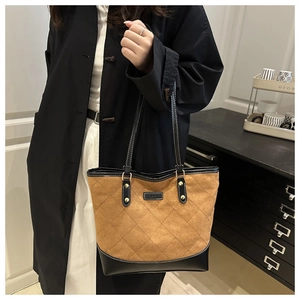 Detail of a brown suede tote bag with black leather trim and quilted rhombus stitching
