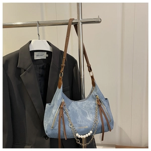Détail du sac cabas en denim avec chaîne dorée à perles et bandoulière marron contrastée