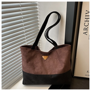 Detalle de bolso tote bicolor con textura de ante marrón y logotipo de triángulo metálico