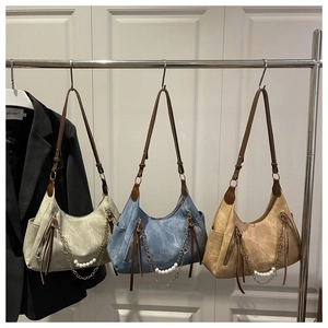 Detalle de bolsos hobo vintage con cadenas de perlas, cremallera con flecos y textura