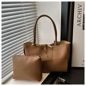 Gros plan du sac cabas tressé marron avec pochette zippée assortie près d'une fenêtre
