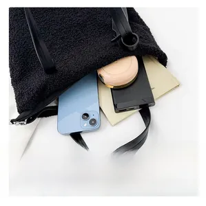 Interno spazioso della borsa a secchiello in peluche nera con cellulare e cosmetici