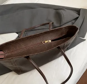Dettaglio di una borsa tote vintage marrone scuro con chiusura a zip dorata di lusso