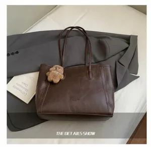 Dettaglio della texture in pelle marrone scuro e del ciondolo a orso sulla borsa