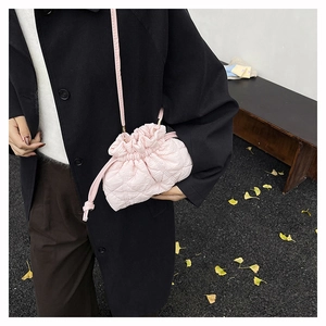 Detailed street style view of pink quilted drawstring shoulder bag with diamond pattern