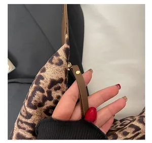 Close-up of leopard print tote bag featuring a leather zipper pull with gold metal stud