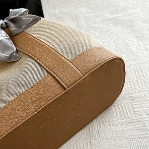 Detail of color-block tote with beige canvas, brown leather stitching, and silk scarf