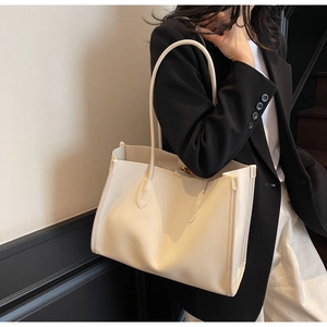 Close-up of minimalist cream tote bag showing smooth faux leather texture and slender strap
