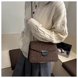 Détail d'un sac bandoulière léopard avec chaîne en métal porté par un mannequin