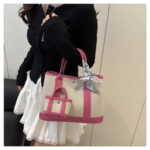 Detailed shot of contrast color tote with mini charm bag and decorative silk scarf