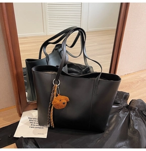 Detalle de bolso tote negro con colgante de osito y reflejo en el espejo de diseño