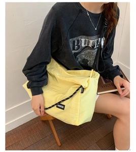 Vue détaillée du sac cabas en nylon jaune avec bandoulière tressée et étiquette