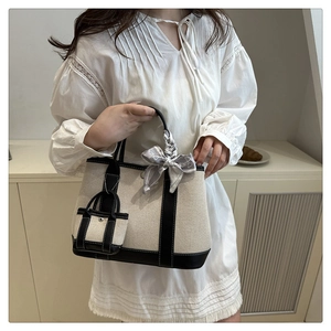 Detail of canvas tote bag with contrast leather trim and decorative floral scarf on handle