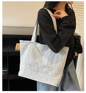 Primer plano del bolso tote de lona azul claro con bordado de corazón y correa de hombro