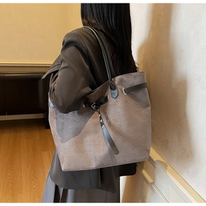 Détail de la texture en daim et de la bandoulière en cuir noir sur un grand cabas taupe