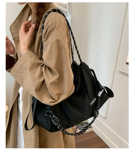 Détail d'un sac cabas noir avec bretelles en corde rayée et étiquette de mode