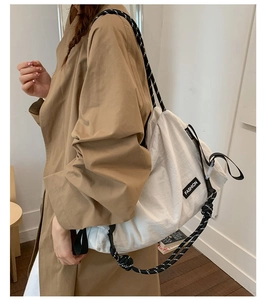 Gros plan d'un sac cabas beige doté de bretelles en corde tressée noires et blanches uniques
