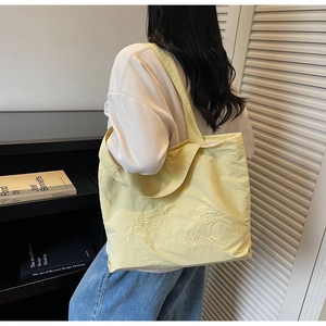Detail of light yellow canvas tote bag featuring embroidered heart and star patterns