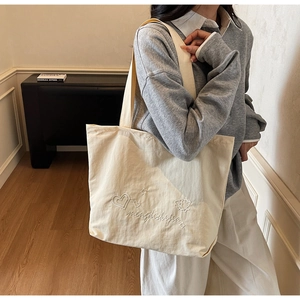 Close-up of cream canvas tote bag featuring high-density heart and star embroidery