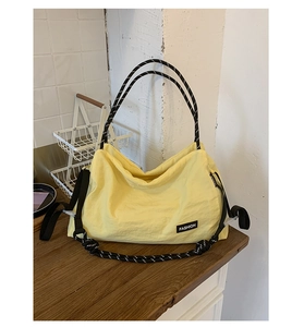 Détail du cabas en nylon jaune avec poignées en corde rayée noir et blanc et logo