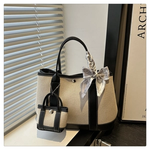 Beige canvas tote bag with black leather trim, mini charm, and heart print silk scarf