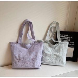 Detail of embroidered star and bear patterns on textured canvas tote bags in lavender and blue