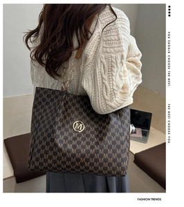 Detail of jacquard tote bag featuring M-pattern texture and gold metal logo charm