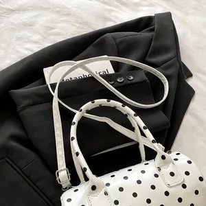 Détail du sac cylindrique à pois avec bandoulière réglable et doubles poignées