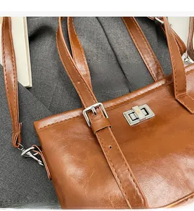 Détail d'un sac marron vintage en cuir brillant avec fermoir rotatif en métal argenté