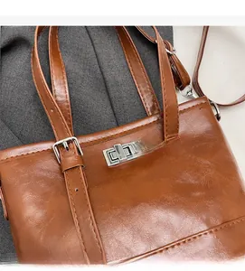 Détail d'un sac marron vintage avec fermoir rotatif argenté et bandoulière réglable