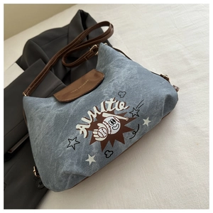 Dettaglio della borsa tote in denim blu con patta in ecopelle marrone e stampa gatto