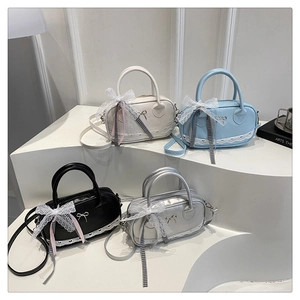 Detail view of stylish handbags in cream, blue, black, and silver with lace and silk ribbons