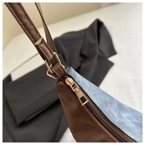 Dettaglio di ecopelle marrone e denim blu con eleganti finiture in metallo dorato