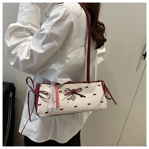 Détail du nœud en ruban rouge et pendentif cœur sur le sac baguette en toile