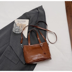 Vue détaillée d'un sac seau vintage marron foncé sur un costume avec décor artistique