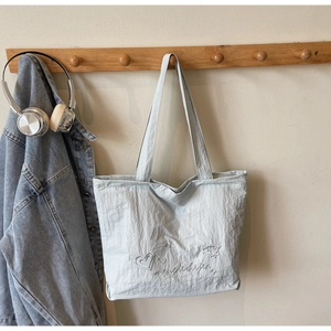 Minimalist light blue canvas tote bag with heart embroidery hanging on a wooden hook