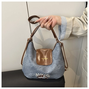 Dettaglio della borsa in denim e pelle marrone con scritte dorate Tidal Dryness