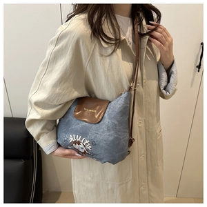 Dettaglio della borsa a tracolla in denim azzurro con patta in pelle marrone e ricamo Annie
