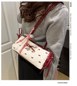 Détail du sac à bandoulière à nœuds rouge et blanc avec dentelle et pendentif cœur